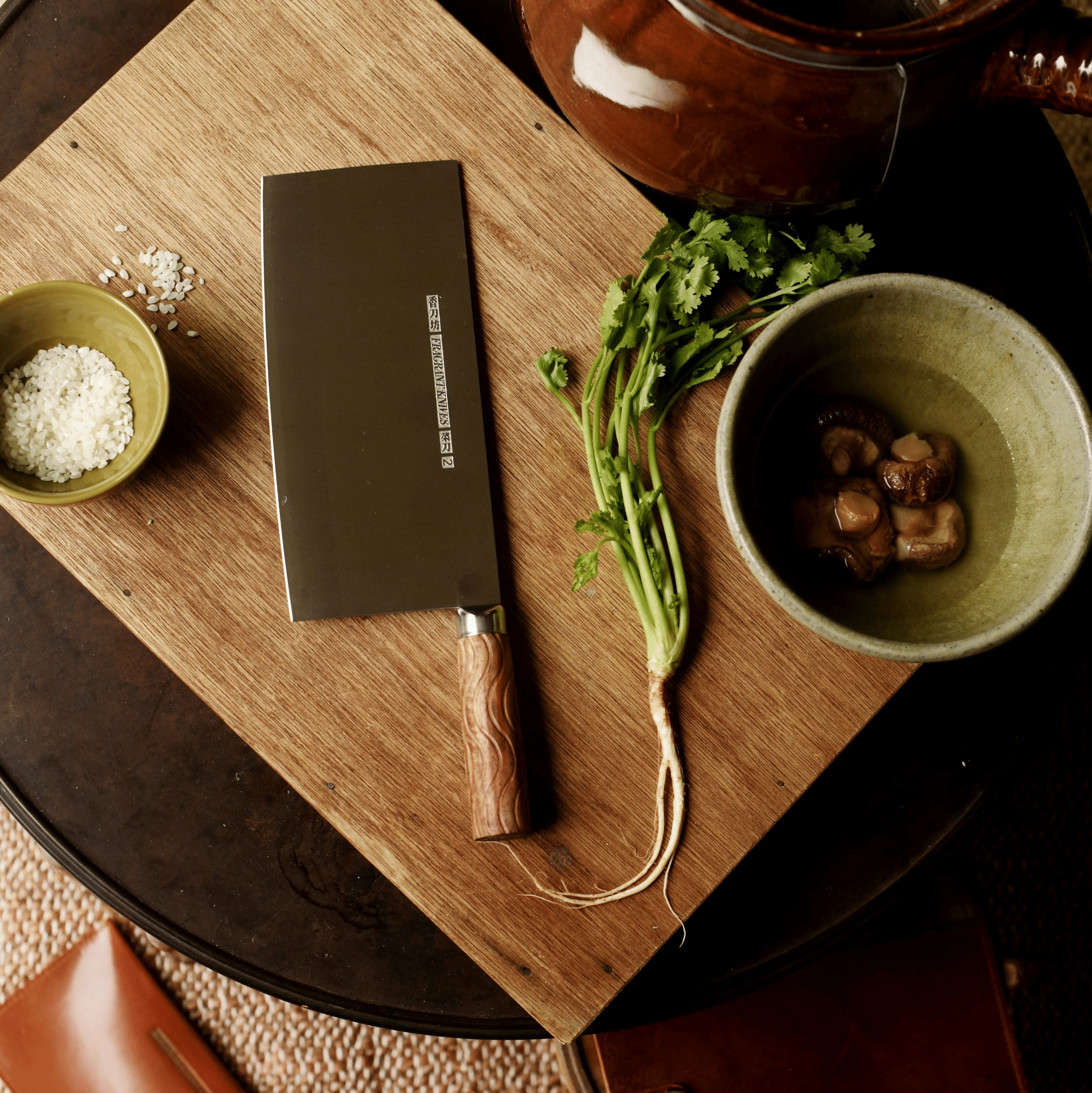 High-carbon steel knife on a wooden cutting board with bowls of Chinese ingredients