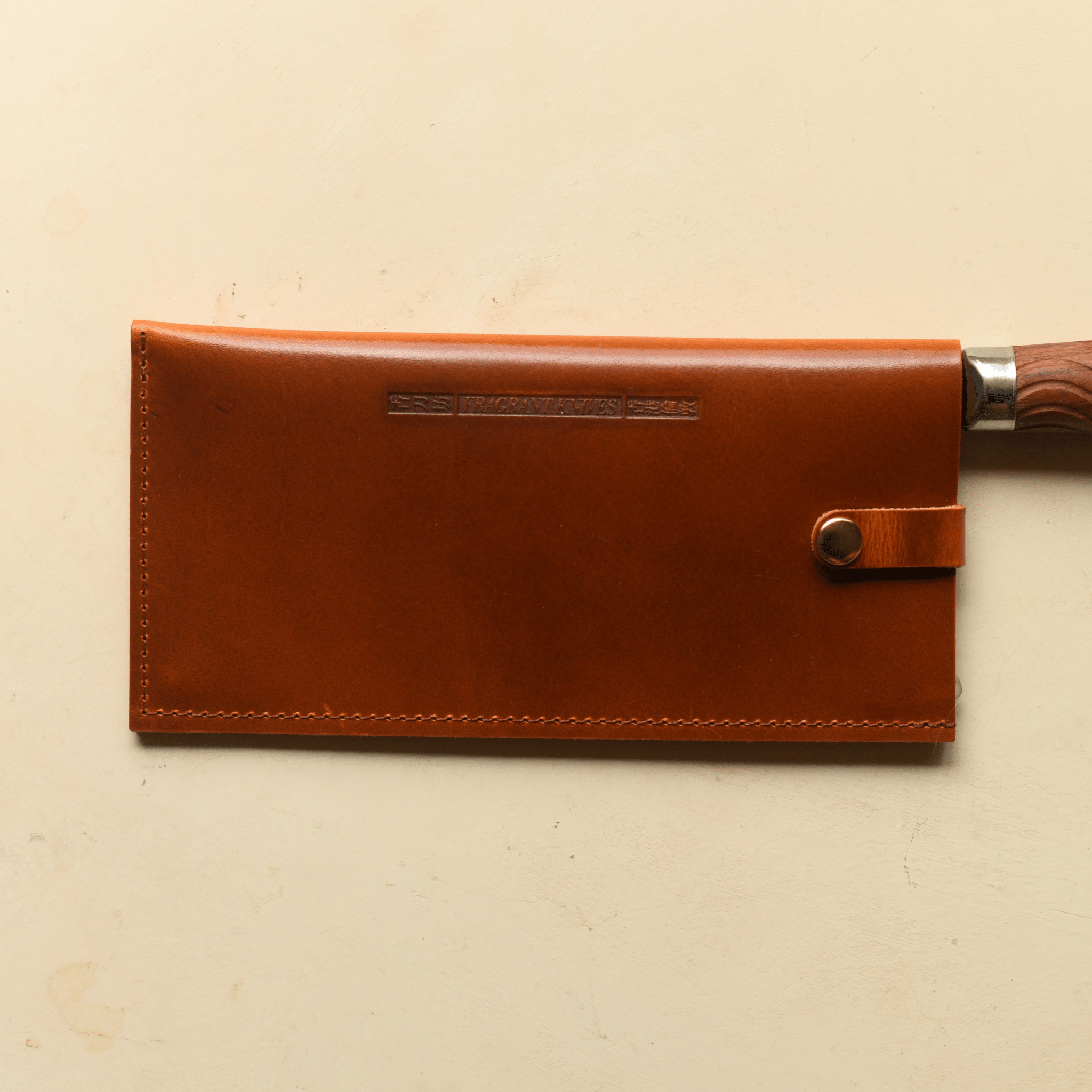 Brown leather sheath with a silver clasp on a beige background