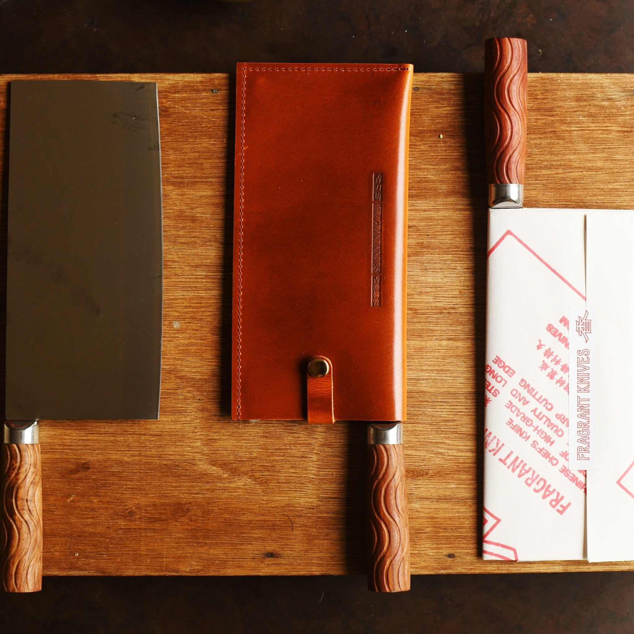 Three knives with sheaths on a wooden cutting board